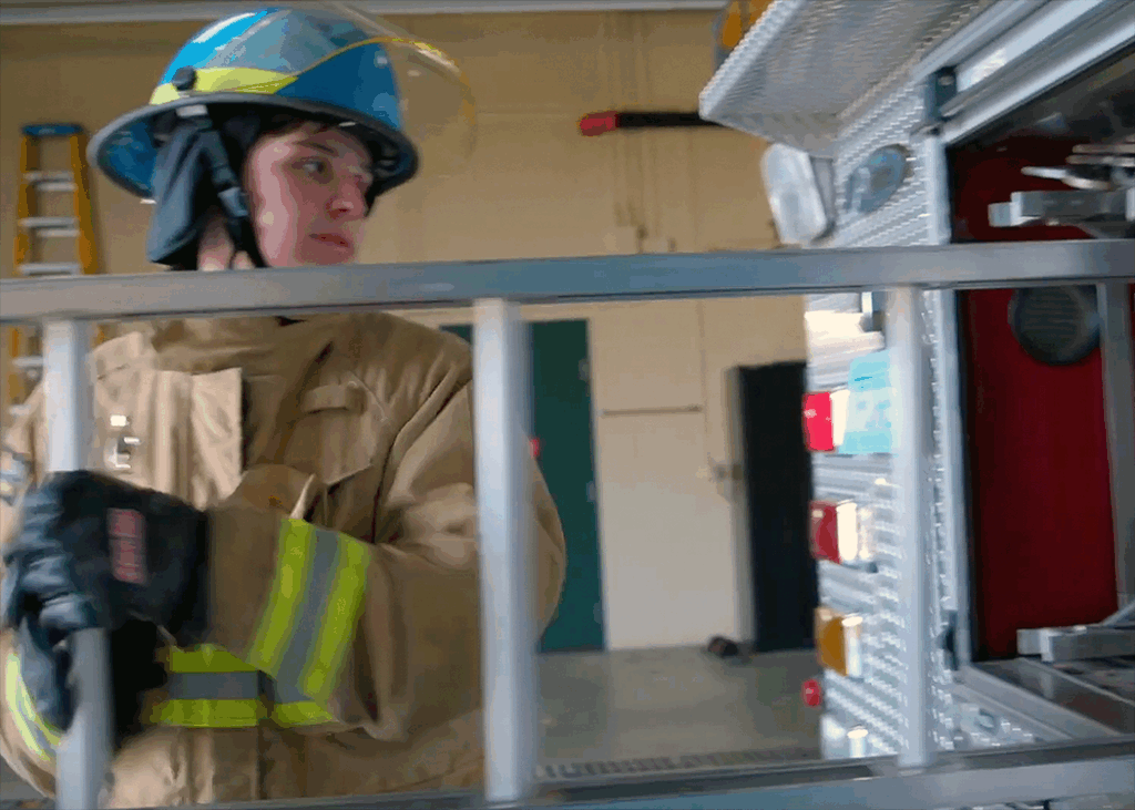 A firefighter pulling a ladder out of a firetruck.