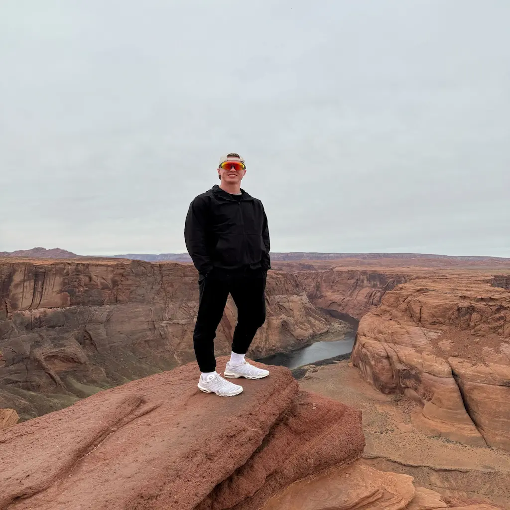 Man smiling at the camera on the edge of a large canyon