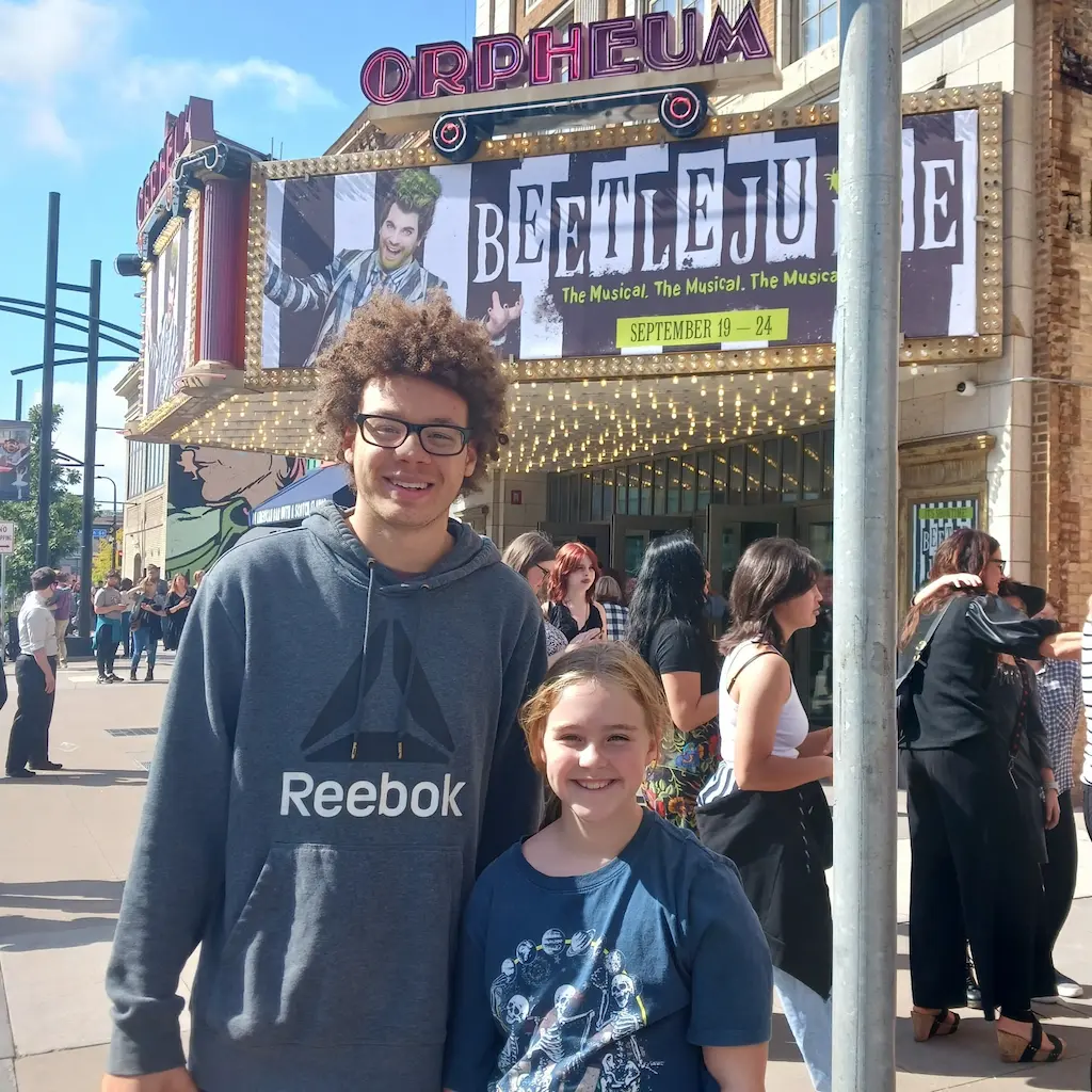 Man and woman smiling at the camera outside a theater