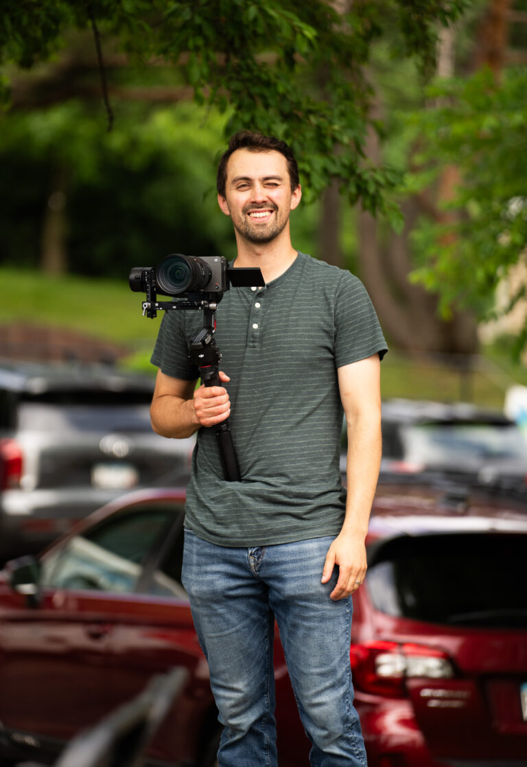 Adrian smiling with his camera in hand