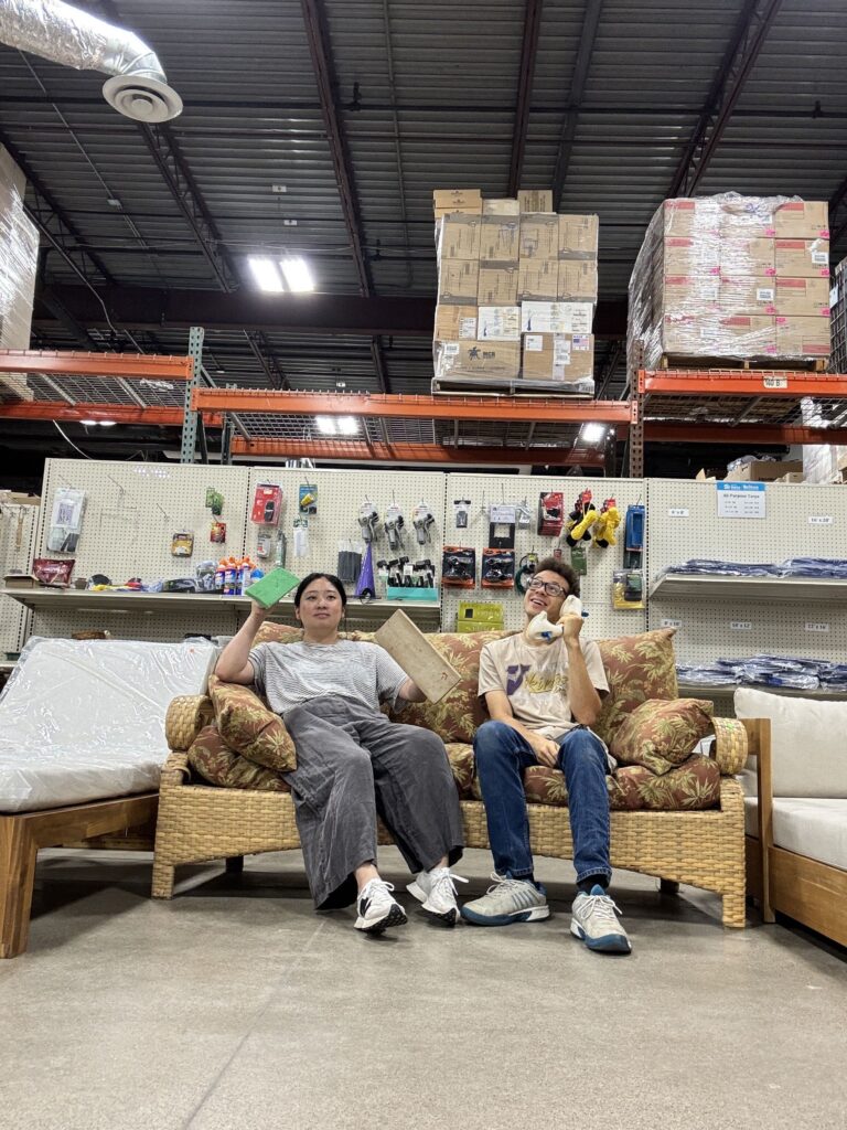 Tyson and Alyssa on a couch in a warehouse with comically large phones
